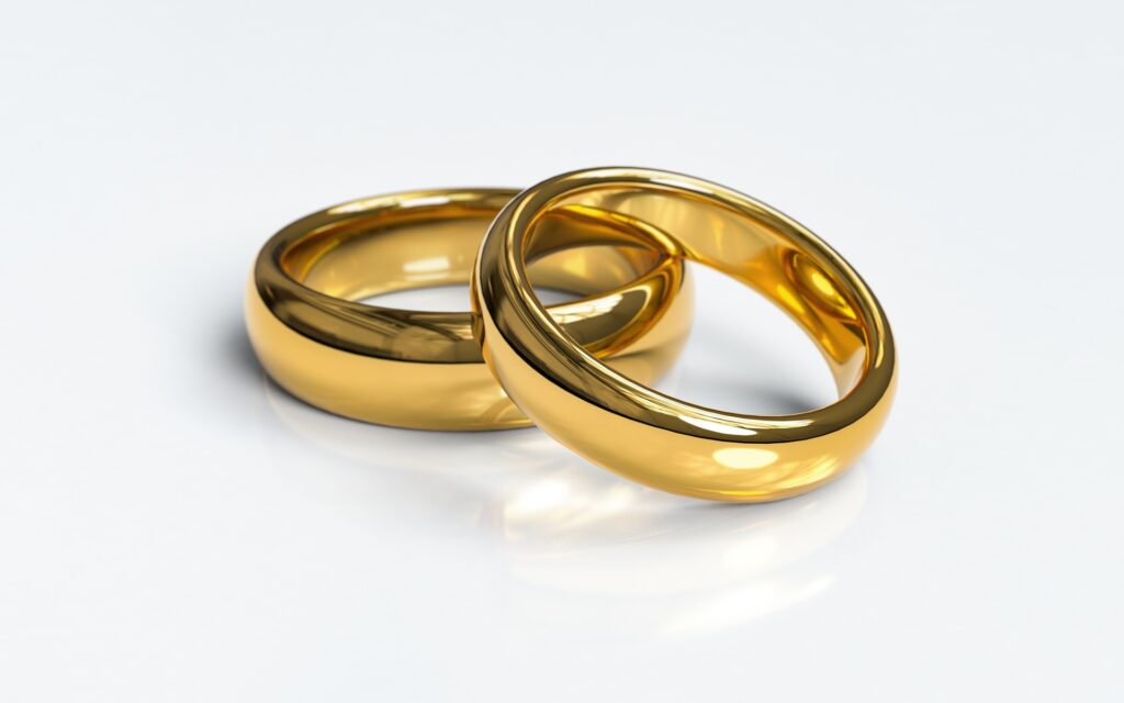 Two intertwined gold wedding rings on white background